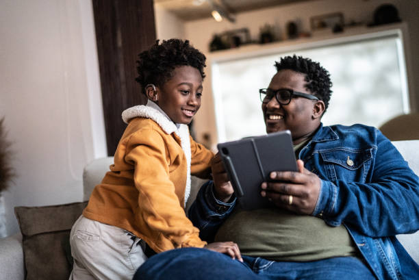 Father showing something on digital tablet to his son at home